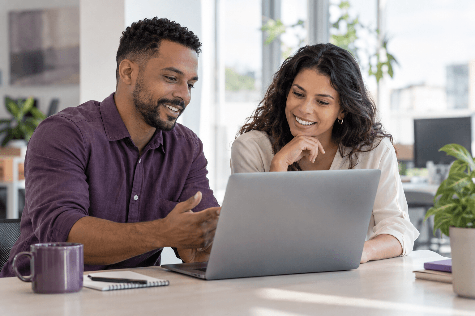 Duas pessoas colaborando com atenção em um notebook